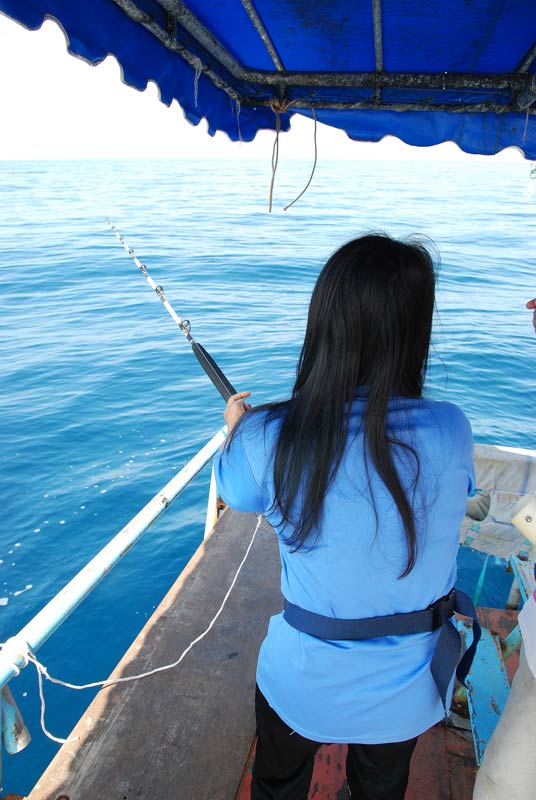 ด้านหลังเรือ  พี่เอ๋  สาวคนเดียวของทริปนี้  กำลังเย่อปลา  จากการลอยสาย