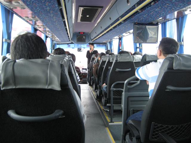 บนรถบัส น้องส้ม city guide กำลังอธิบายโปรแกรมว่าจะไปไหนและทำอะไรบ้าง