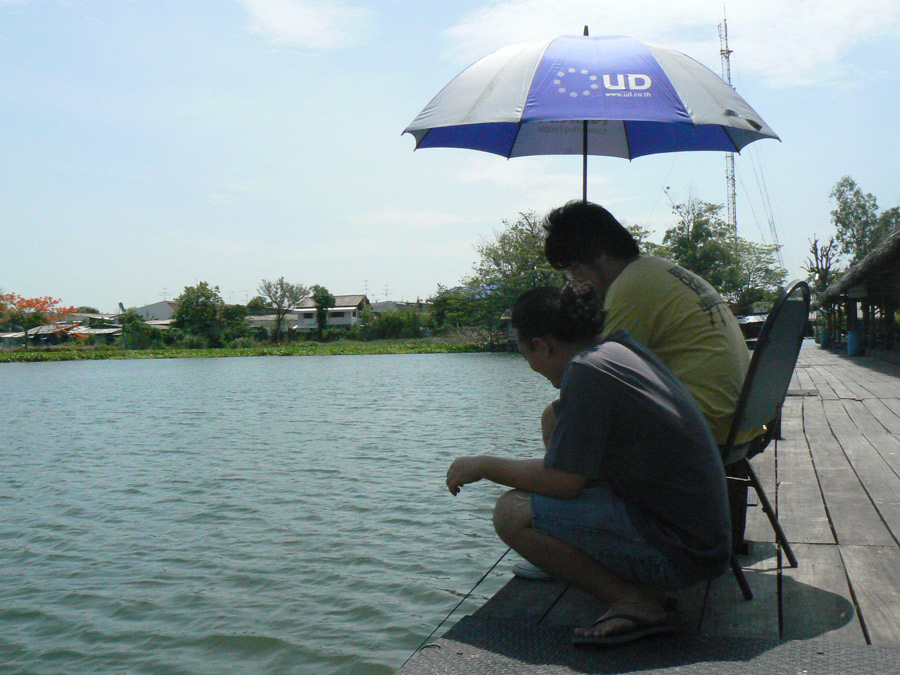 คุณชายจอมแห้งร้านพิซซ่าชื่อดังย่านประดิพัทธ์12นั่งลุ้นปลานิลอยู่พร้อมสหายนั่งถือร่มให้อยู่บนเก้าอี้ 