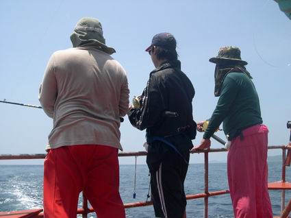 ที่บริเวณท้ายเรือ...ยืนถือคันเบ็ดลากปลาโอ .(Skipjack Tunu)..อาจมี ทูน่าครีบเหลือง (Yellowfin Tuna) แ
